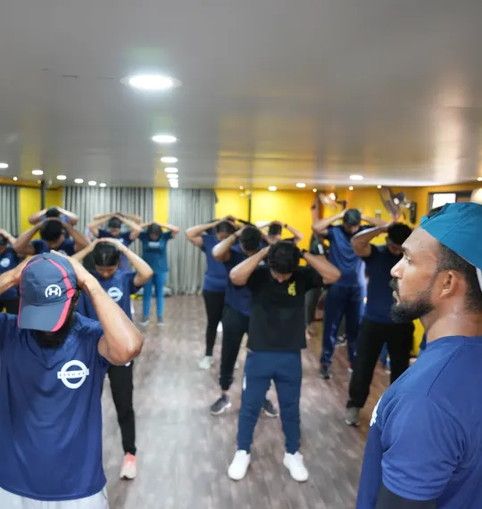 a group of people performing a shoulder exercise in a gym.